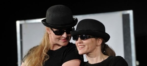 Zwei Frauen mit schwarzen Sonnenbrillen und schwarzen Melonen stehen nebeneinander.
