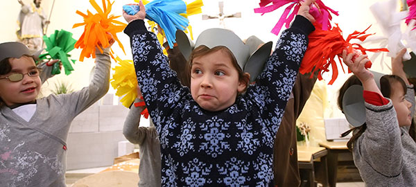Kinder tanzen mit bunten Pompoms. Sie tragen selbstgebastelte Mäuseohren auf dem Kopf.
