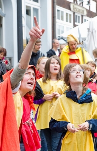 Eine Frau erklärt Kindern einen Teil der Hildesheimer Stadtgeschichte. Alle tragen Kostüme in rot und gelb.