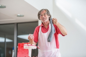 Ein Mann hält eine graue Socke hoch. In der anderen Hand hält er zermatschten Teig, den er aus einem Kuchen entnommen hat.