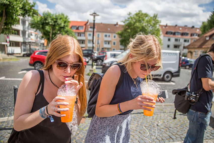 Zwei Frauen stehen auf einem Platz in Hildesheim und trinken Cocktails aus Strohhalmen.