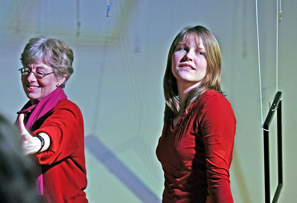 Zwei Frauen auf der Bühne blicken in unterschiedliche Richtungen.
