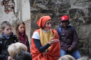 Eine Frau im Kostüm spricht mit einer Gruppe von Schulkindern.