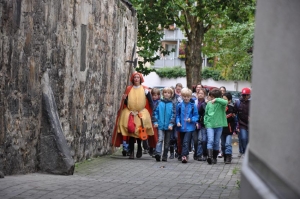 Eine Frau im Kostüm führt eine Gruppe von Kindern durch eine Hildesheimer Straße.