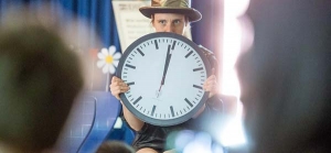 Eine Person hält eine große Uhr vor ihr Gesicht.
