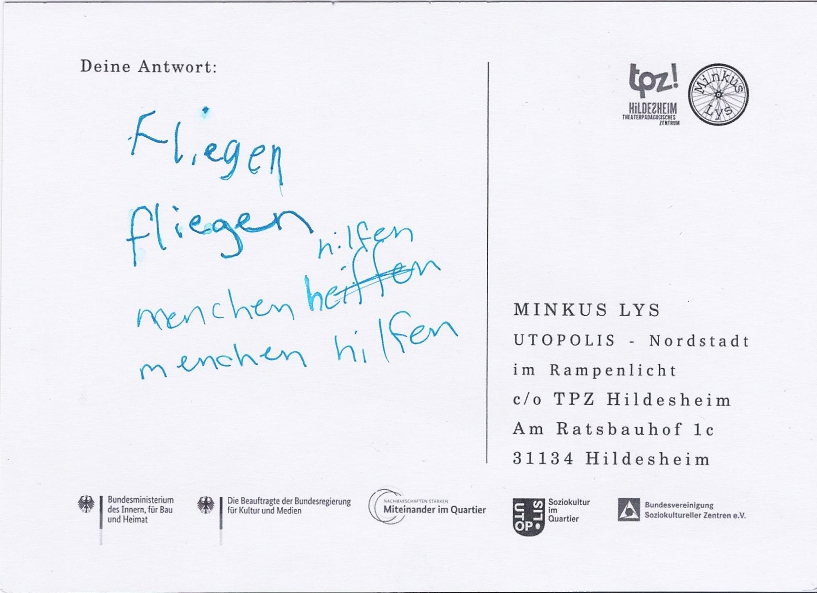 Die Rückseite einer Postkarte. Auf der Karte steht: "fliegen fliegen menschen hilfen menschen hilfen".