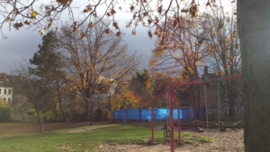 Ein leerer Park im Herbst. Rechts steht eine rote Schaukel.