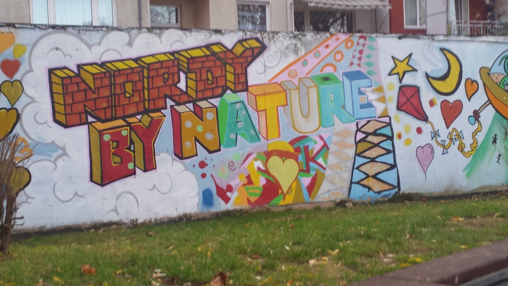 Eine Mauer mit Graffiti. Auf der Mauer steht in bunten Farben: "Nordy by Nature".
