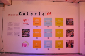 Fotos und Zitate hängen aufgereiht an einer Wand. Darüber steht der Schriftzug: "Galerie Ah!"
