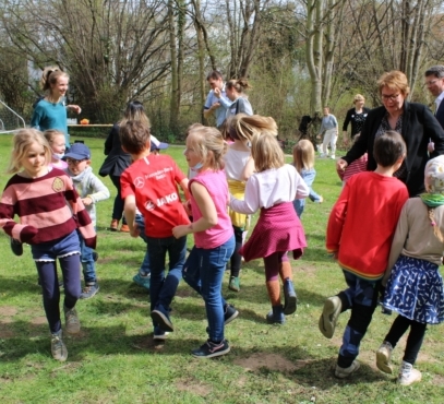 Kinder hüpfen über eine Wiese. Zwischen ihnen hüpft auch die Sozialministerin Daniela Behrens und der Oberbürgermeister von Hildesheim, Ingo Meyer.