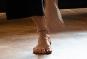 Die nackten Füße einer Frau sind zu sehen. Der rechte Fuß wird schnell angehoben, sodass er nur verschwommen zu sehen ist.