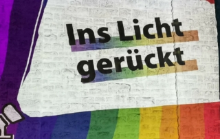 Vor einem bunten Hintergrund steht die Aufschrift "Ins Licht gerückt".