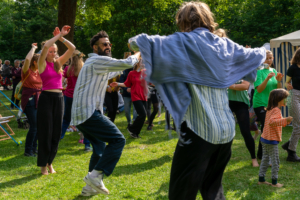 Menschen tanzen zusammen auf einer Wiese.