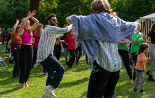 Menschen tanzen zusammen auf einer Wiese.