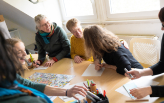 Menschen sitzen um einen Tisch herum und lachen.