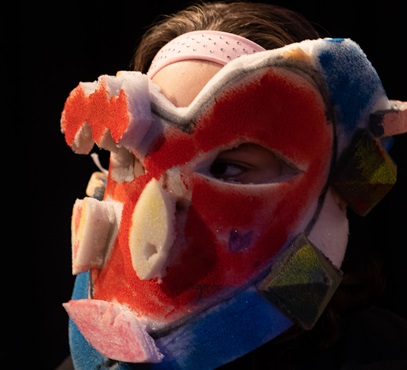 Ein Kind trägt eine bunte, selbstgebastelte Maske aus Schaumstoff.