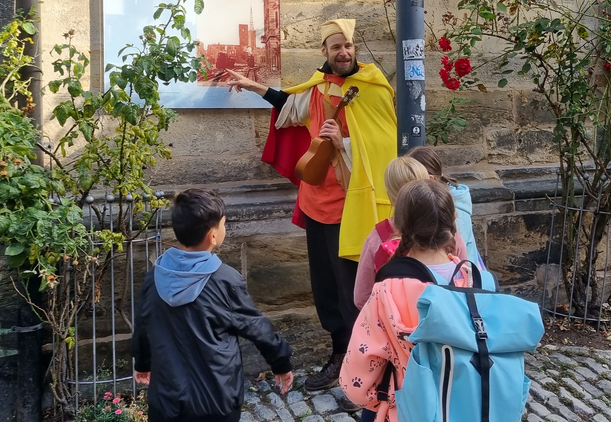 Ein Mann in einem mittelalterlichen Kostüm erklärt Kindern die Hildesheimer Stadtgeschichte.